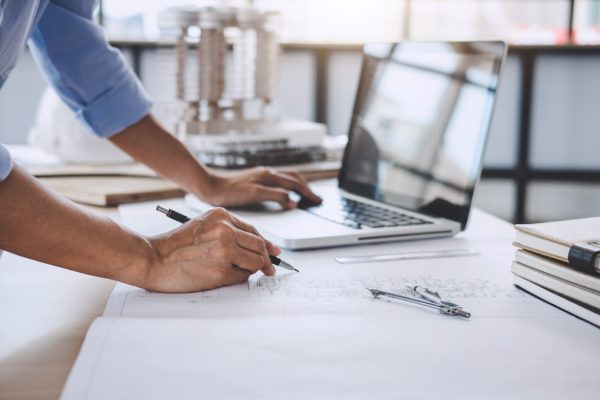 Construction concept, Hands of architect or engineer working for new project plan on blueprint, model building and engineering tools in working site